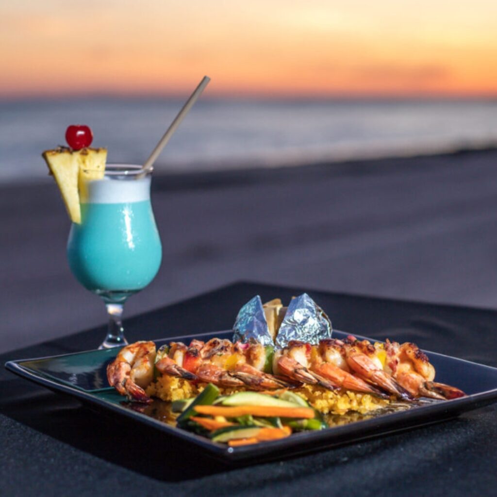 Seafood dinner plate and tropical cocktail served at sunset at Puesta del Sol restaurant in Rocky Point.
