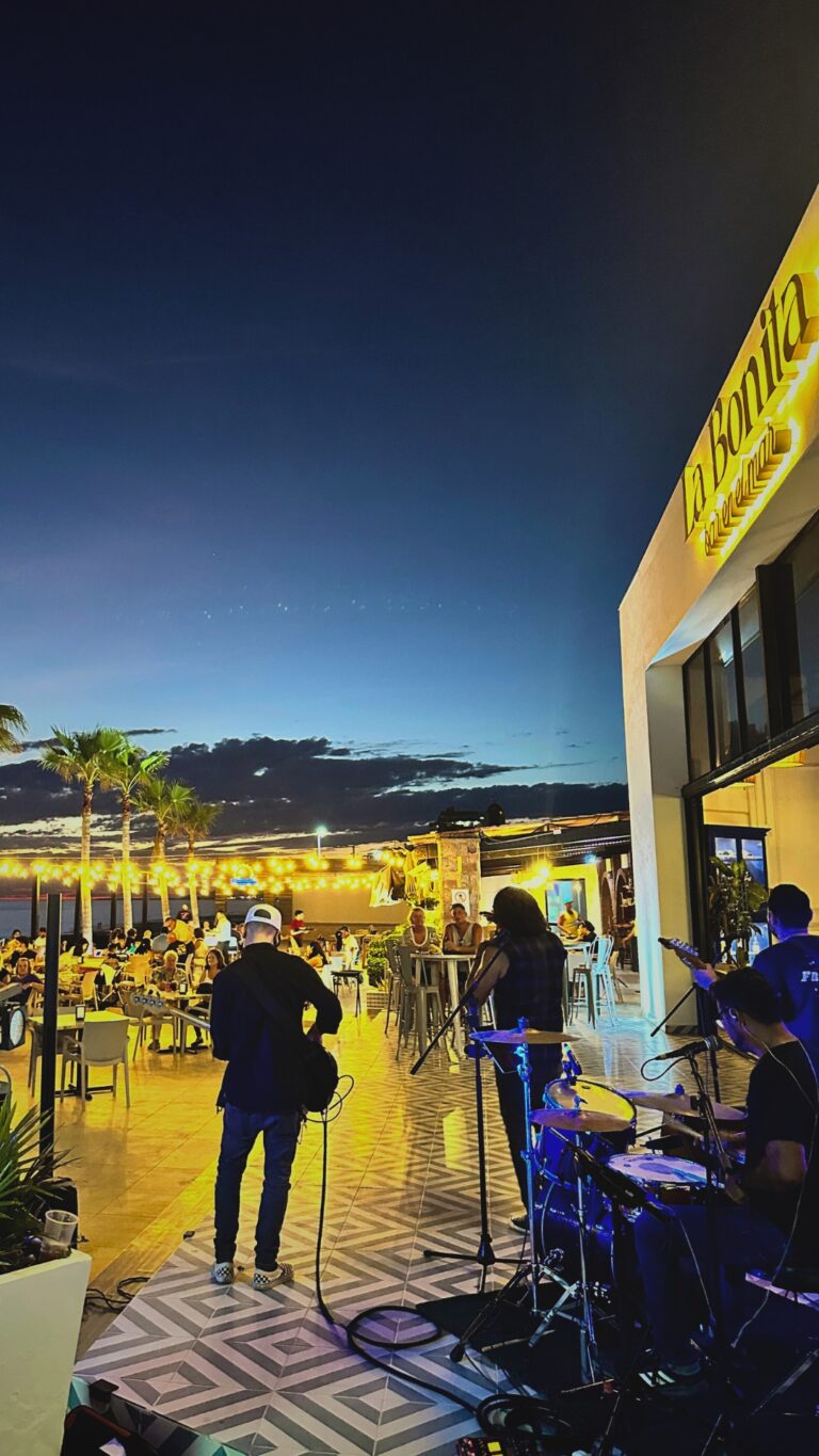 Musicians playing live music at Puesta del Sol’s oceanfront terrace at sunset, with guests dining and the Sea of Cortez in the background.